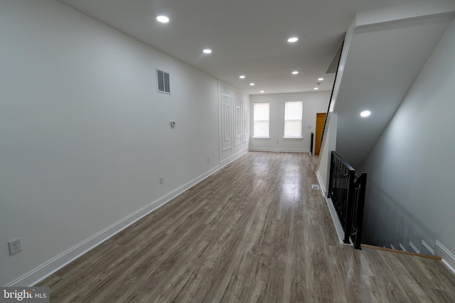 unfurnished living room with wood finished floors, baseboards, and recessed lighting