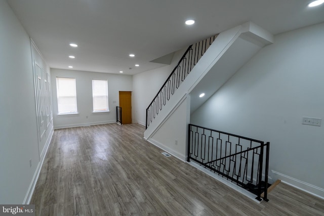 unfurnished living room with wood finished floors, baseboards, and recessed lighting