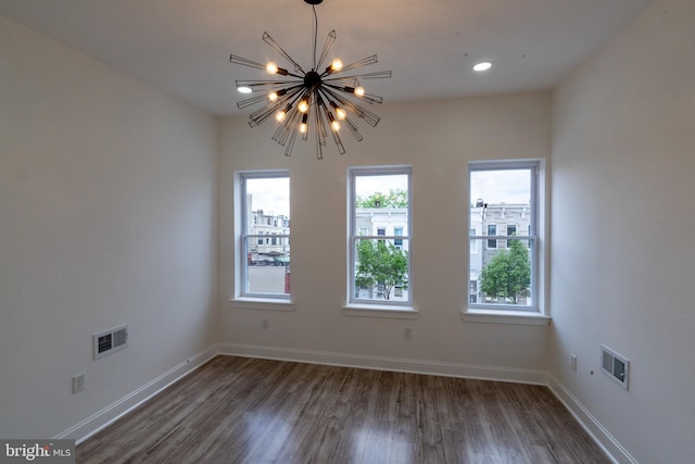 unfurnished room with a chandelier, wood finished floors, and baseboards