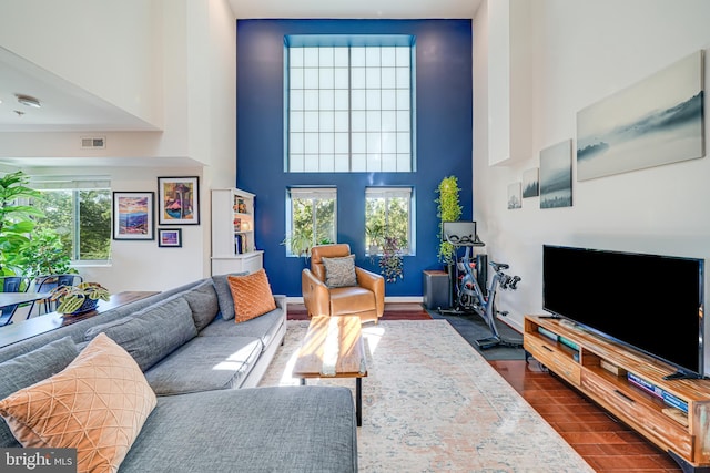 living area with healthy amount of natural light, a high ceiling, and baseboards