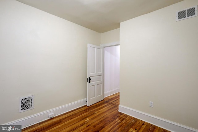 unfurnished room with baseboards, wood finished floors, and visible vents