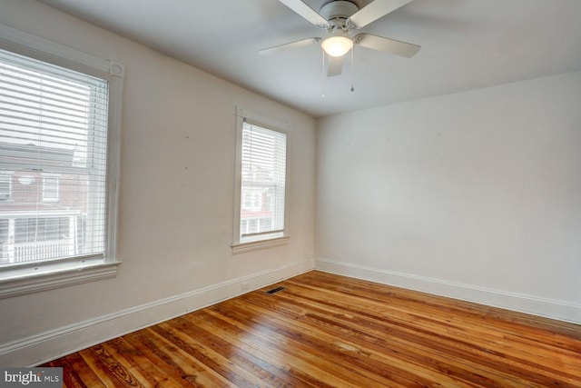 spare room with hardwood / wood-style floors, visible vents, baseboards, and ceiling fan