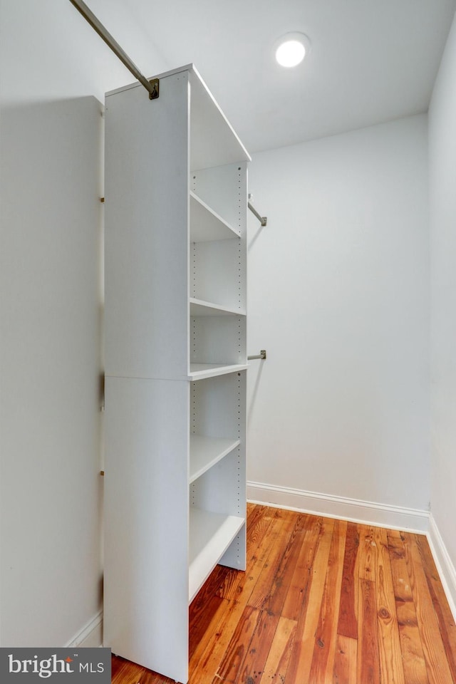 walk in closet with wood finished floors