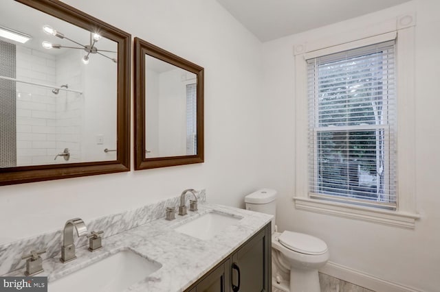 full bathroom with toilet, a sink, double vanity, and tiled shower