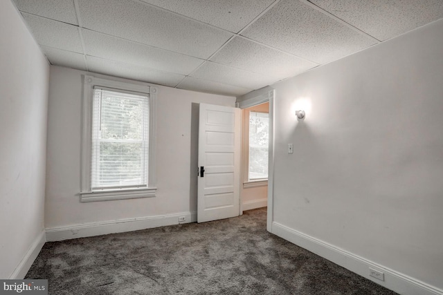 carpeted spare room with baseboards and a paneled ceiling
