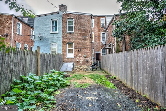 rear view of house featuring a fenced backyard and brick siding