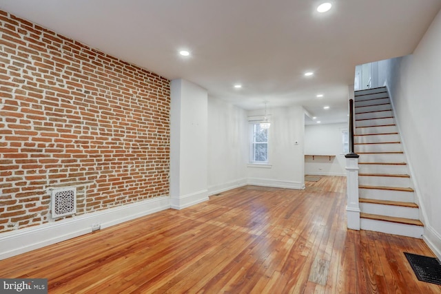 unfurnished living room featuring baseboards, hardwood / wood-style flooring, visible vents, and stairway