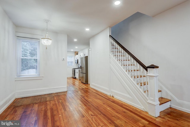 staircase with baseboards, a wealth of natural light, hardwood / wood-style floors, and recessed lighting