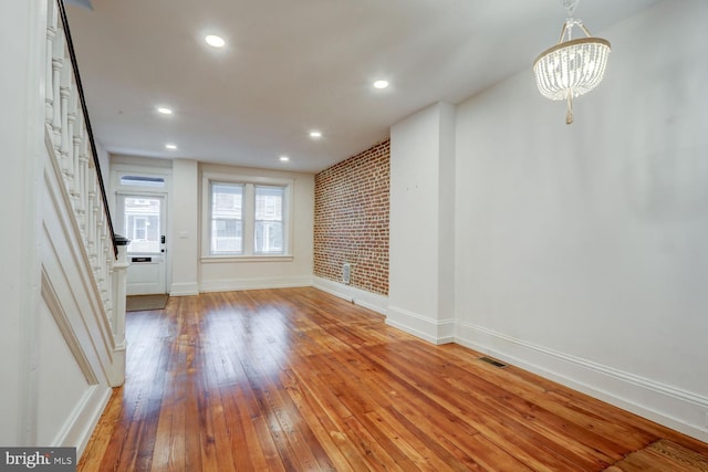 unfurnished living room featuring recessed lighting, an inviting chandelier, baseboards, hardwood / wood-style flooring, and stairs