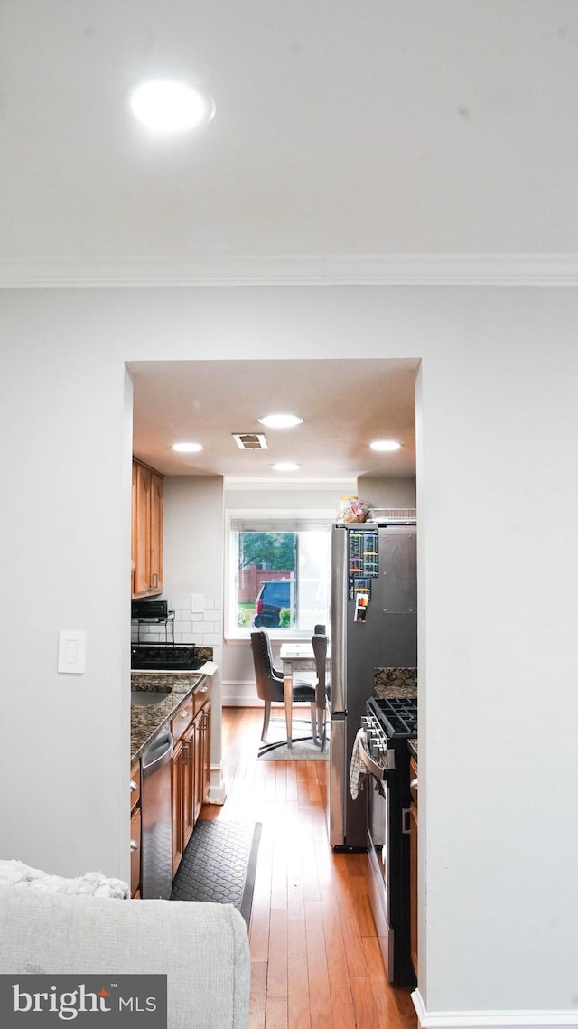 218 Stevenson Sq, Alexandria, VA 22304 - kitchen with appliances with stainless steel finishes, brown cabinets, light wood-type flooring, and crown molding