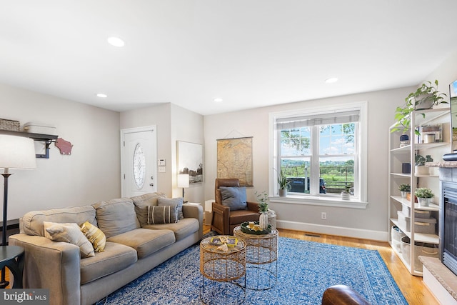 living room featuring recessed lighting, baseboards, and light wood-type flooring