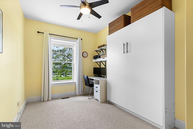 unfurnished office featuring baseboards, ceiling fan, light colored carpet, and visible vents