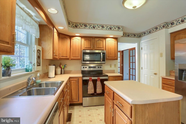 kitchen with a center island, a sink, brown cabinets, stainless steel appliances, and light countertops