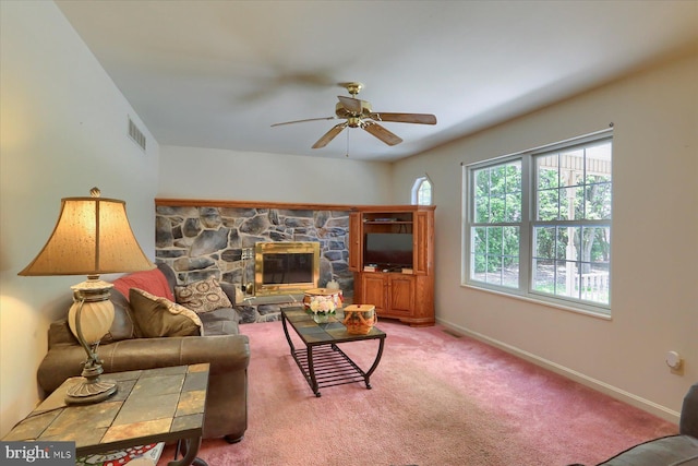 living area with a stone fireplace, ceiling fan, baseboards, carpet flooring, and visible vents