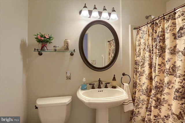 bathroom with toilet, a sink, and a shower with curtain