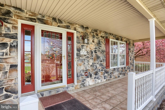 doorway to property with stone siding and covered porch