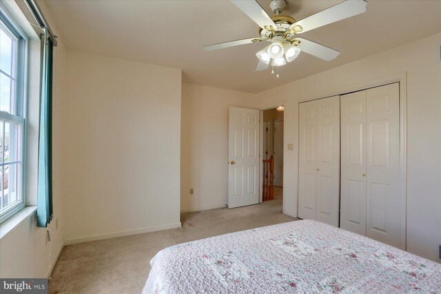 bedroom featuring visible vents, light carpet, a closet, baseboards, and ceiling fan