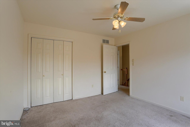 unfurnished bedroom with baseboards, visible vents, light colored carpet, a ceiling fan, and a closet