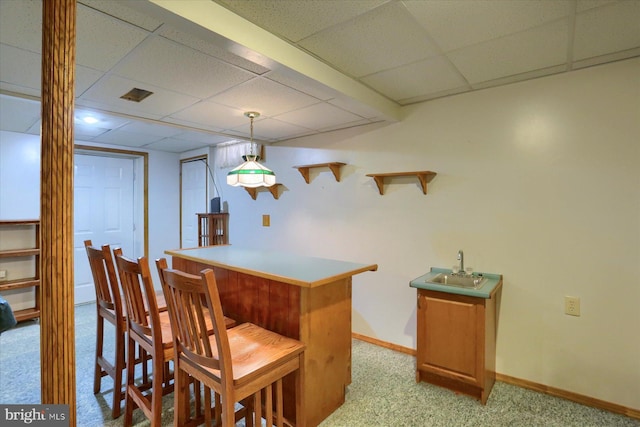 interior space with light colored carpet, baseboards, a dry bar, and a drop ceiling