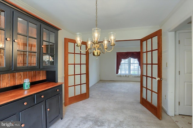 unfurnished dining area featuring french doors, a chandelier, and crown molding