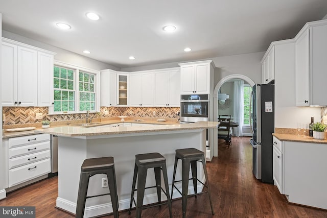 7098 Garden Walk, Columbia, MD 21044 - kitchen featuring appliances with stainless steel finishes, white cabinets, a kitchen breakfast bar, a sink, and light stone countertops
