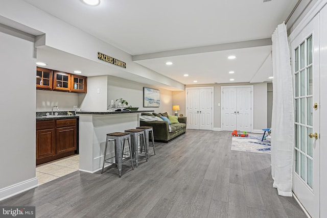 7098 Garden Walk, Columbia, MD 21044 - kitchen featuring light wood-type flooring, a kitchen bar, a sink, glass insert cabinets, and open floor plan