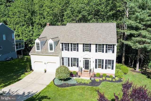 7098 Garden Walk, Columbia, MD 21044 - colonial home with concrete driveway, a chimney, roof with shingles, a front yard, and an attached garage