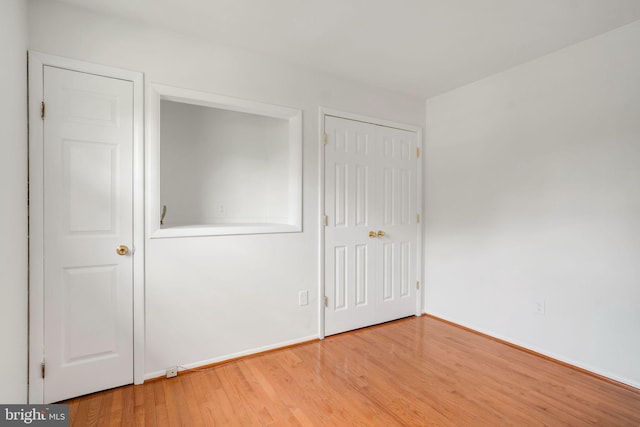 unfurnished bedroom with baseboards, light wood-style floors, and a closet