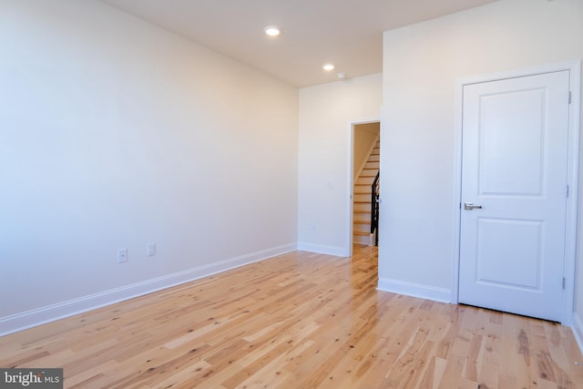 unfurnished room with light wood-style flooring, baseboards, recessed lighting, and stairs