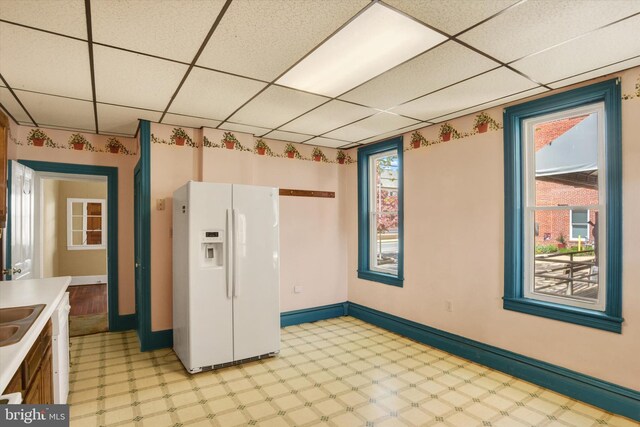 spare room featuring plenty of natural light, a paneled ceiling, and light floors