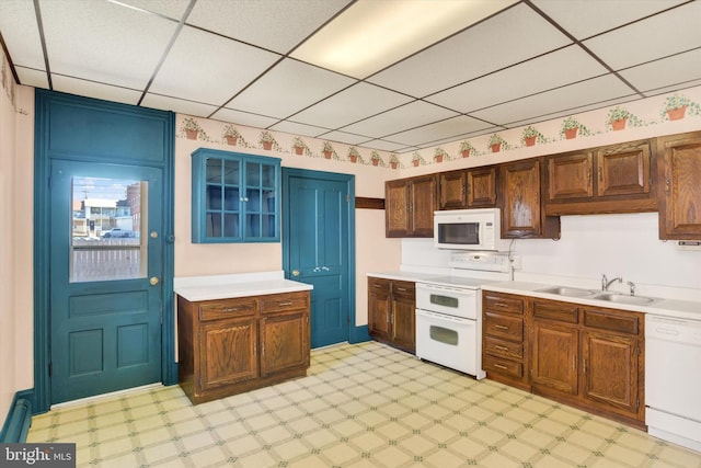 kitchen featuring white appliances, light floors, light countertops, a paneled ceiling, and a sink