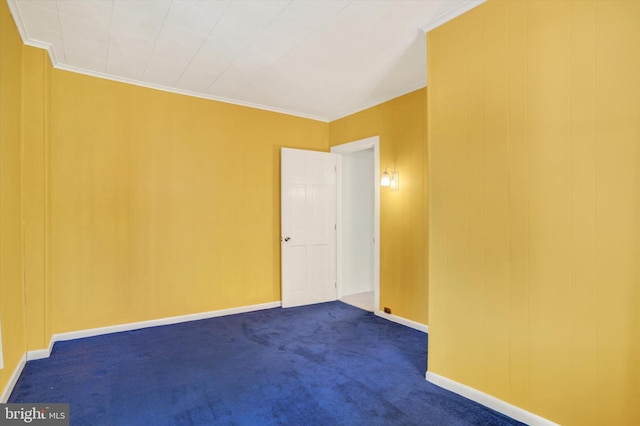 empty room featuring baseboards, ornamental molding, and dark colored carpet