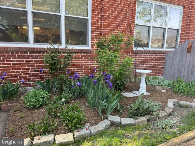 view of side of home featuring brick siding and fence