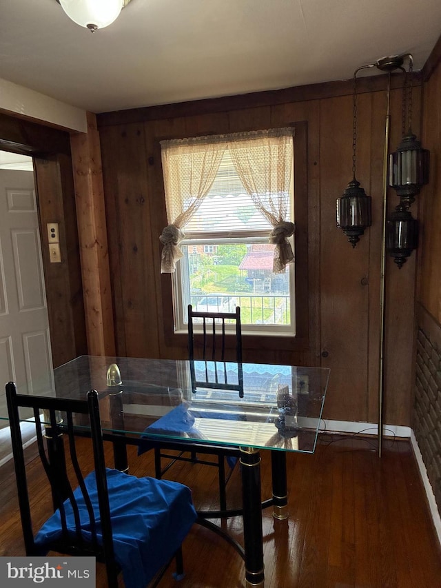 dining space featuring wood finished floors and wood walls