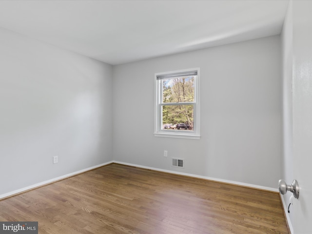 empty room featuring visible vents, baseboards, and wood finished floors