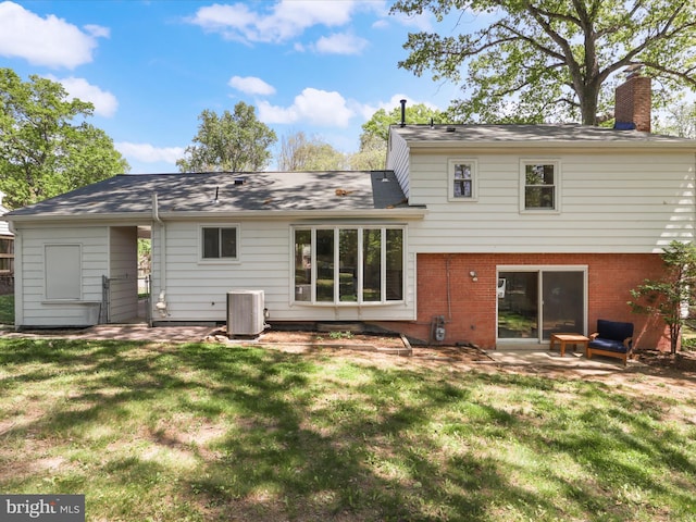 back of property with a lawn, brick siding, central AC unit, and a chimney
