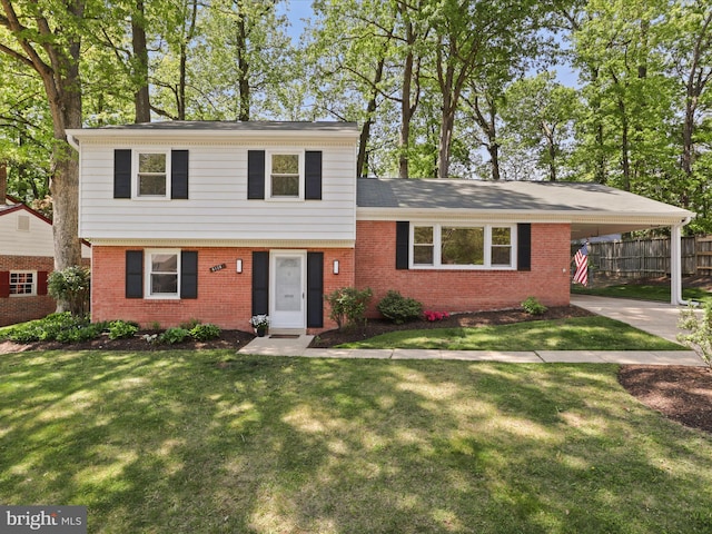 split level home featuring brick siding, a front lawn, fence, and a carport