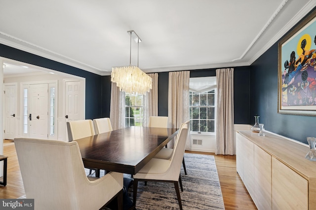 dining room featuring light wood-type flooring, an inviting chandelier, and crown molding