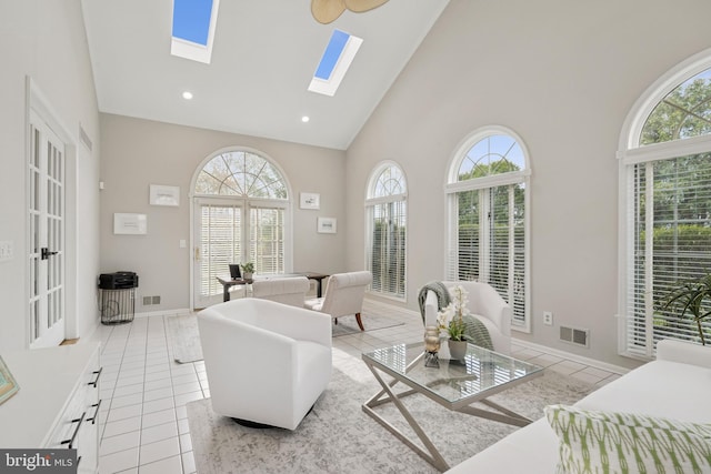 living area featuring a skylight, visible vents, high vaulted ceiling, and light tile patterned floors