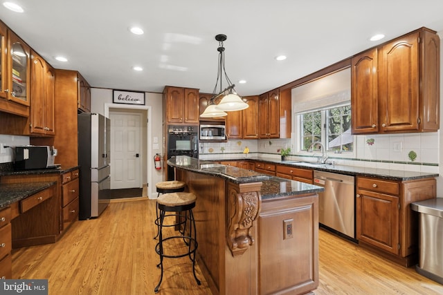 kitchen featuring a center island, a sink, a breakfast bar area, stainless steel appliances, and light wood finished floors