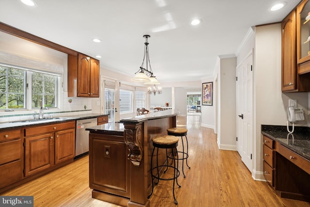 kitchen with a sink, crown molding, a kitchen island, dishwasher, and a breakfast bar