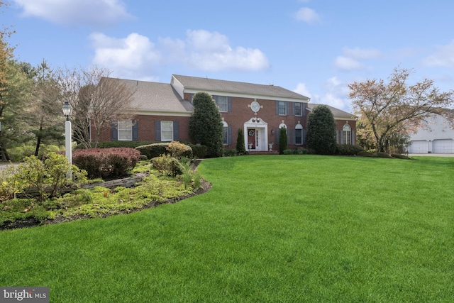 georgian-style home with brick siding and a front yard
