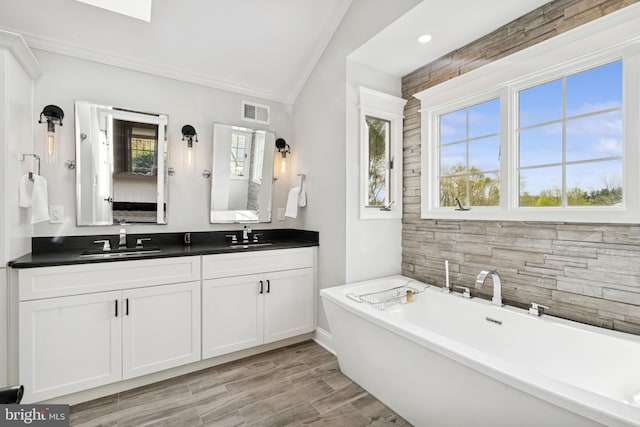 bathroom with visible vents, a sink, a freestanding bath, and a healthy amount of sunlight