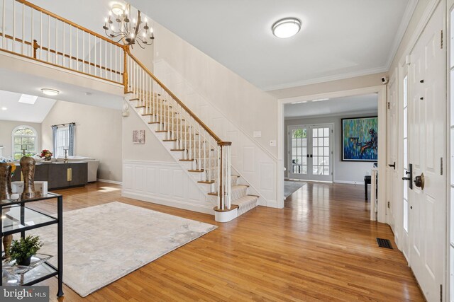 entrance foyer with stairway, an inviting chandelier, visible vents, and light wood-style flooring