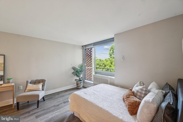 bedroom with radiator heating unit, wood finished floors, and baseboards