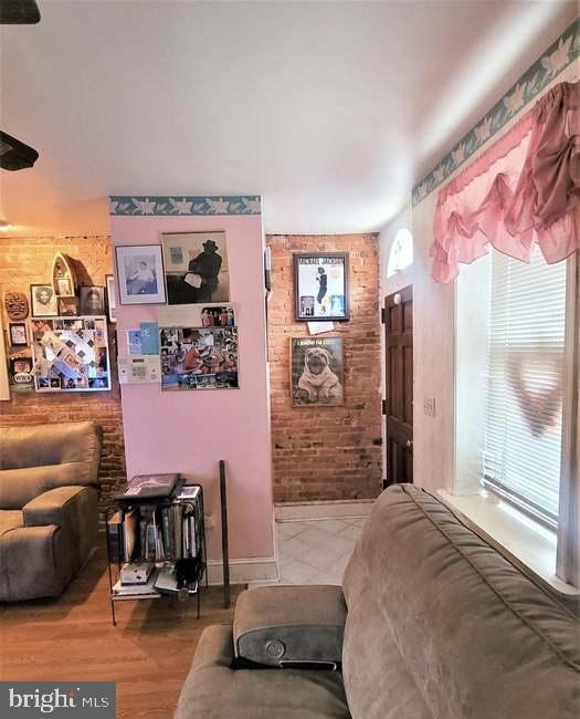 living room with brick wall and wood finished floors