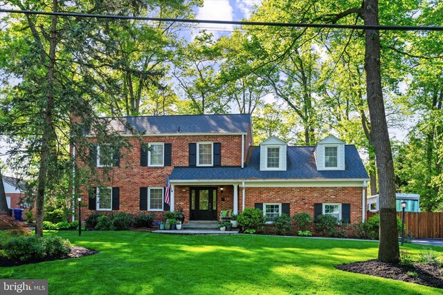 view of front facade featuring fence, a front yard, and brick siding