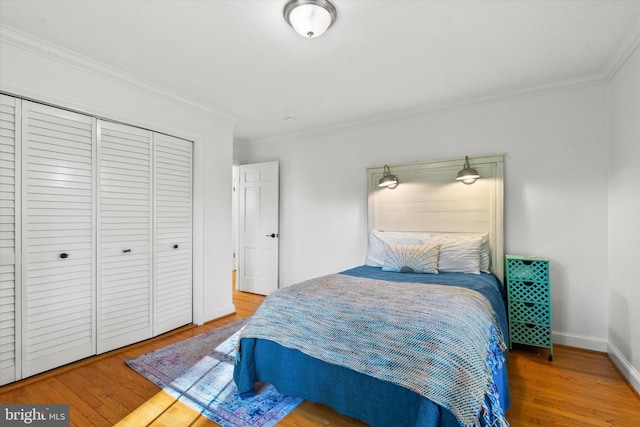 bedroom featuring ornamental molding, a closet, wood finished floors, and baseboards