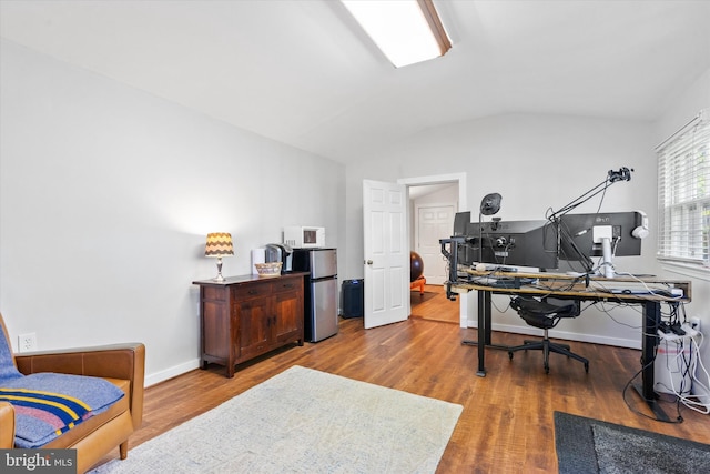 office area featuring wood finished floors, vaulted ceiling, and baseboards