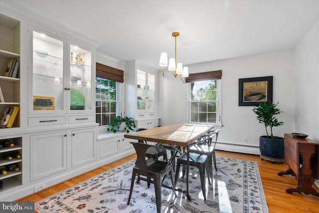 dining room featuring a baseboard heating unit, an inviting chandelier, and light wood-style floors